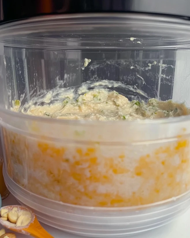 Blending Pistachio Cottage Cheese Cheesecake Batter Blending pistachio cottage cheese cheesecake batter in a plastic food processor with visible curds and pistachio bits