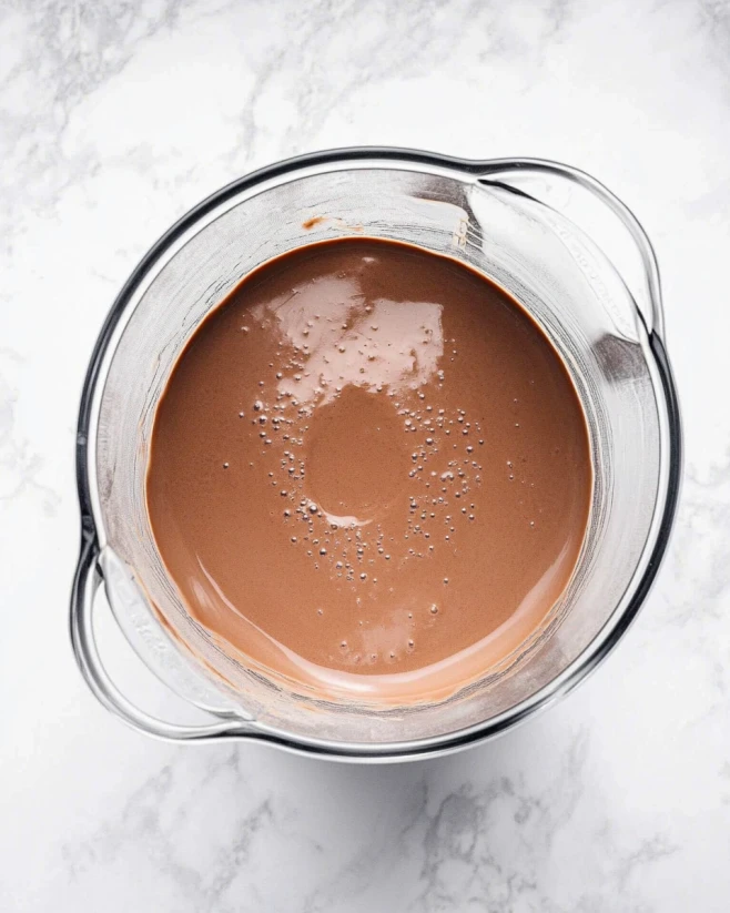 blended-cottage-cheese-chocolate-mousse-mixture.webp Blended cottage cheese chocolate mousse mixture in a clear blender on a marble surface